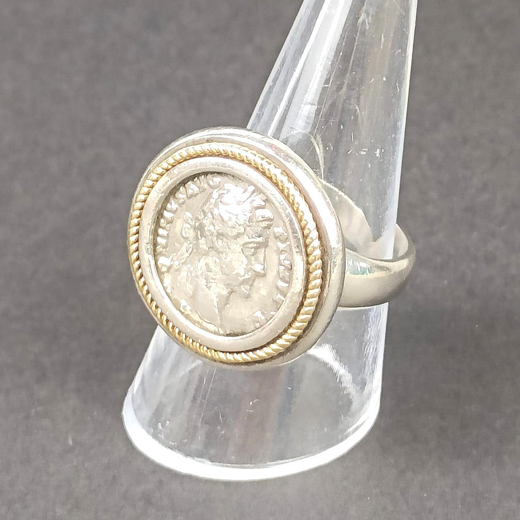 A SILVER RING HOLDING A ROMAN COIN.