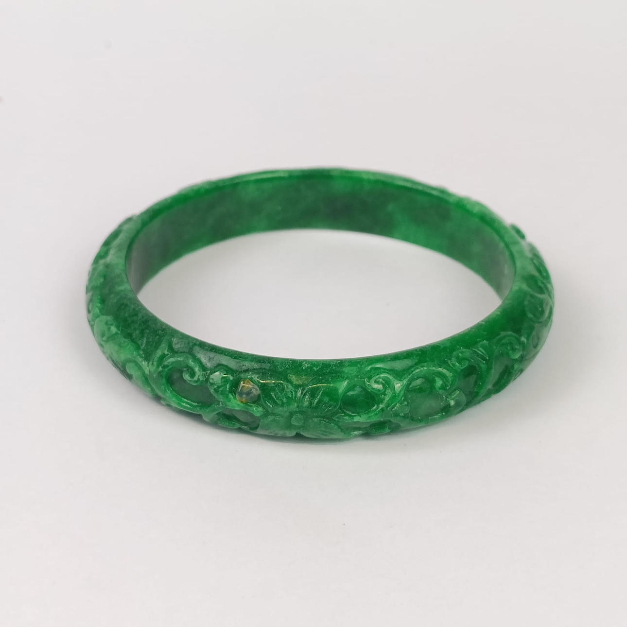 A CARVED JADE/HARDSTONE BANGLE.