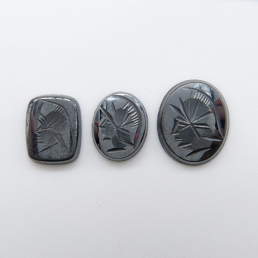 THREE CARVED HEMATITE STONES.