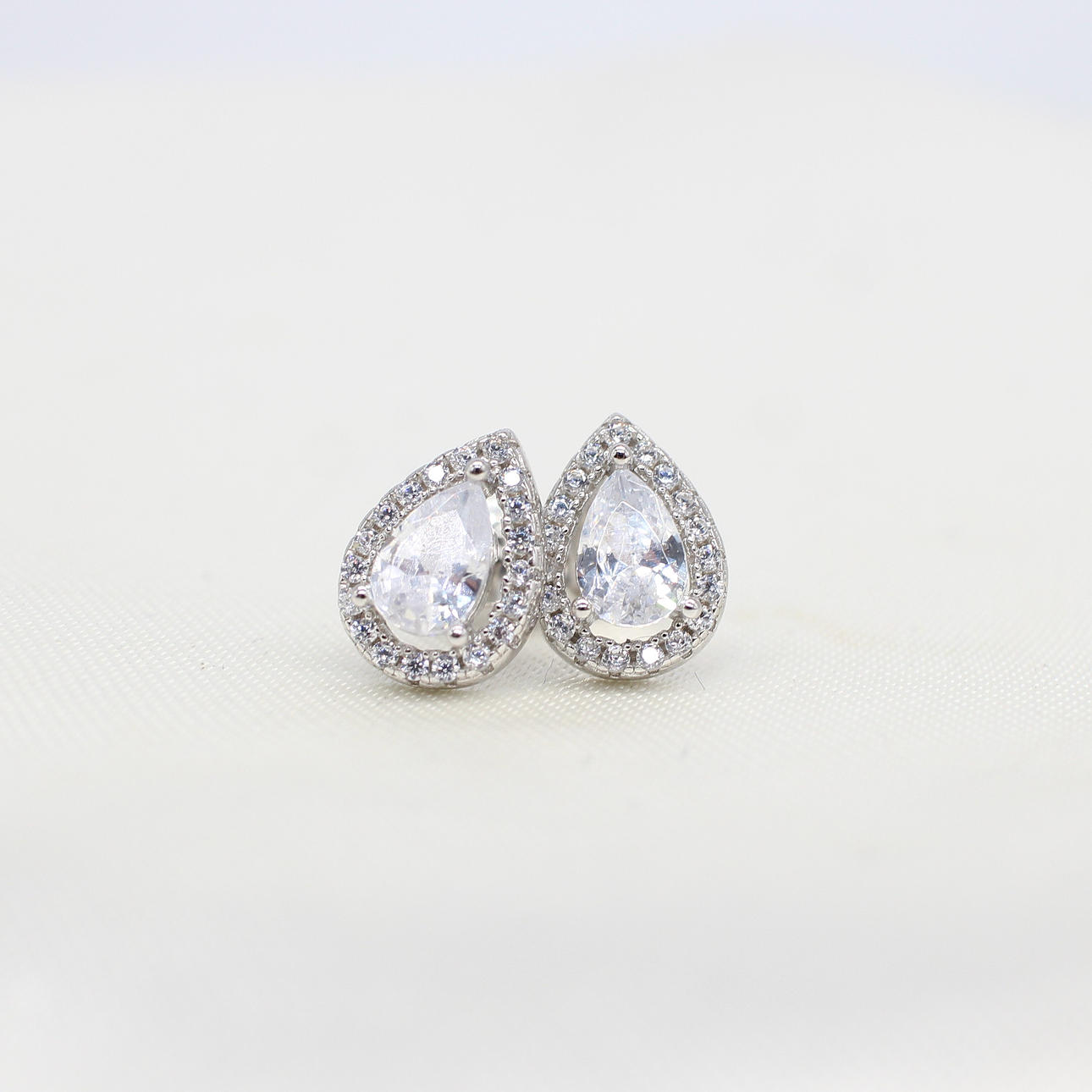 SILVER PEAR SHAPED HALO STUDS.