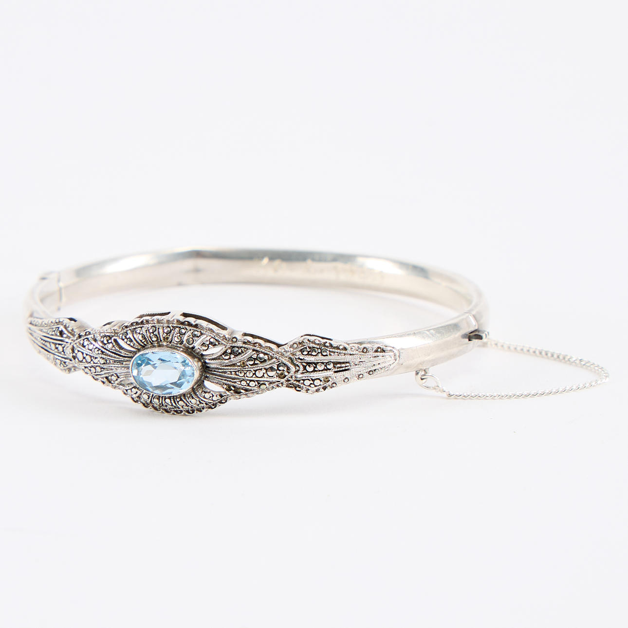 A silver bangle with blue stones.