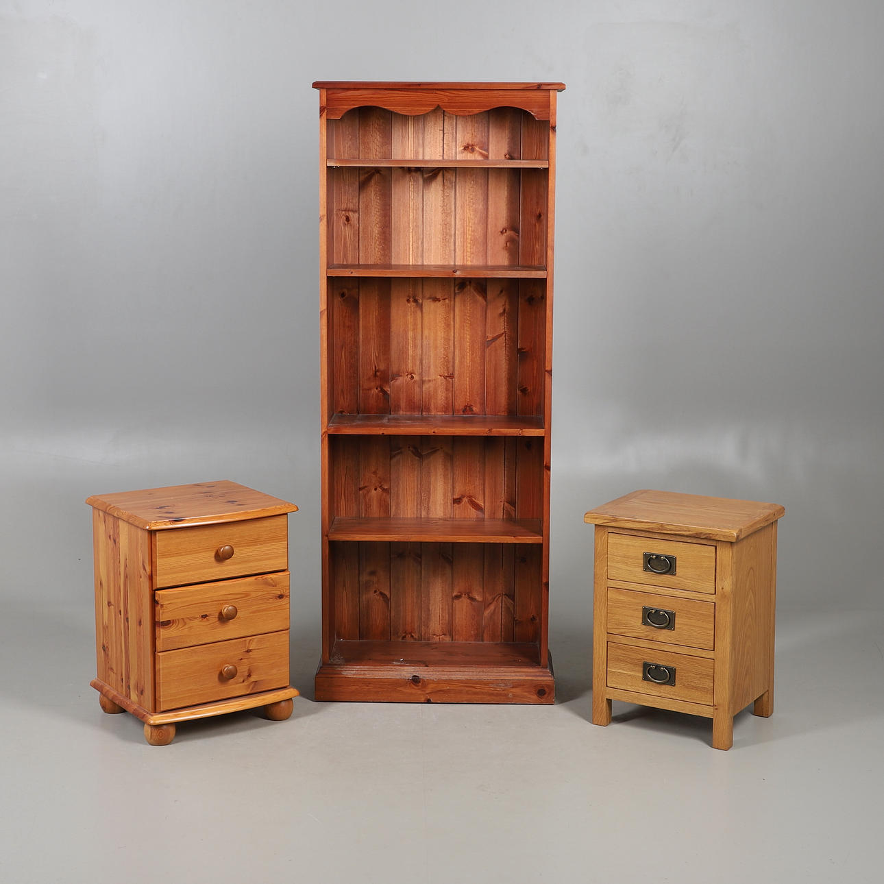 A MODERN STAINED PINE SHELVING UNIT, AND TWO THREE DRAWER BEDSIDE CHESTS (3).