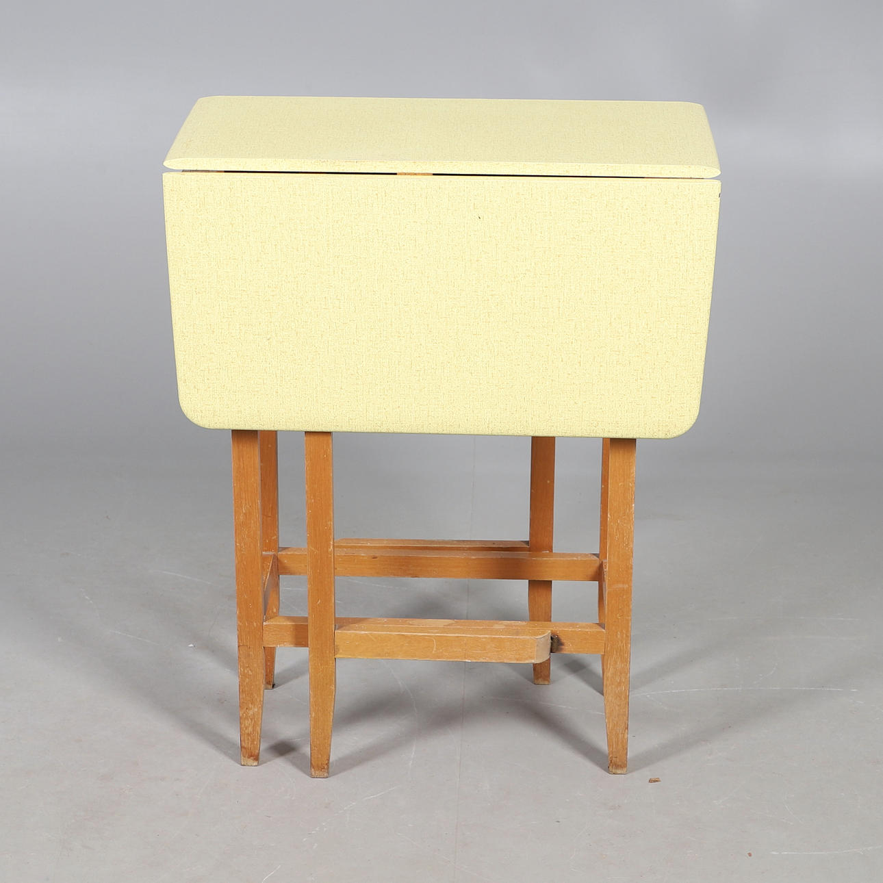 A 1960S YELLOW FORMICA TOP DROP LEAF TABLE.