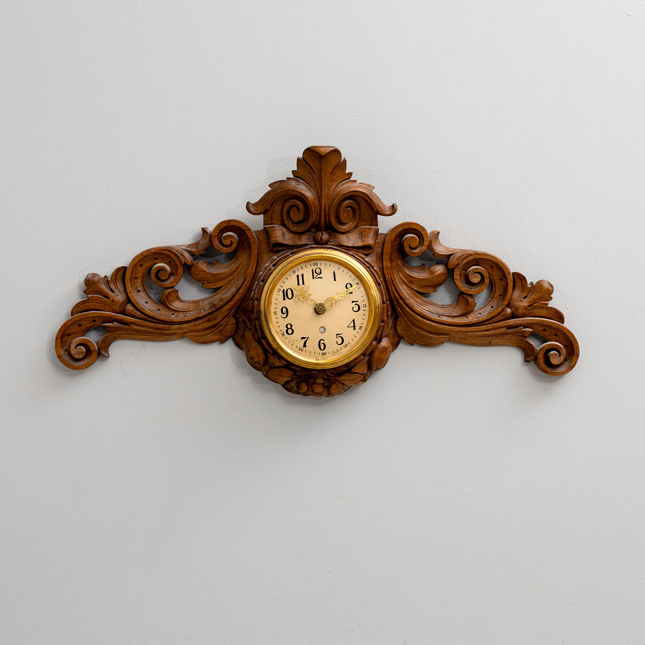 A carved wooden wall clock, circa 1900.