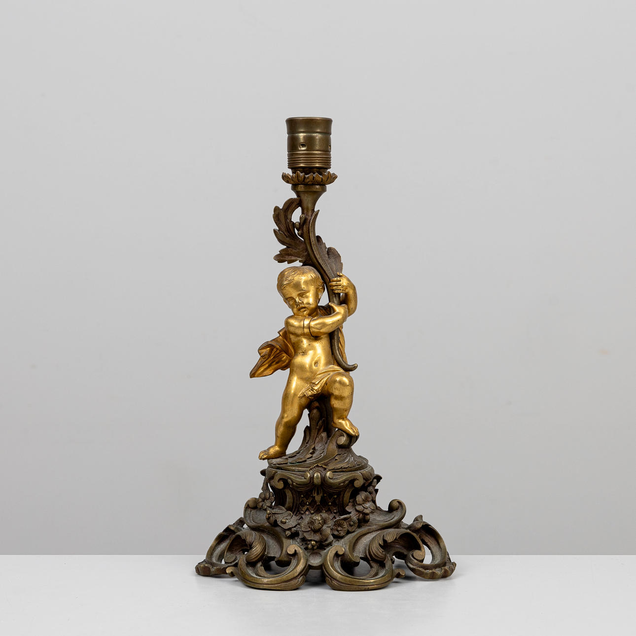 A partially gilded bronze table lamp, decorated by putti, circa 1900.