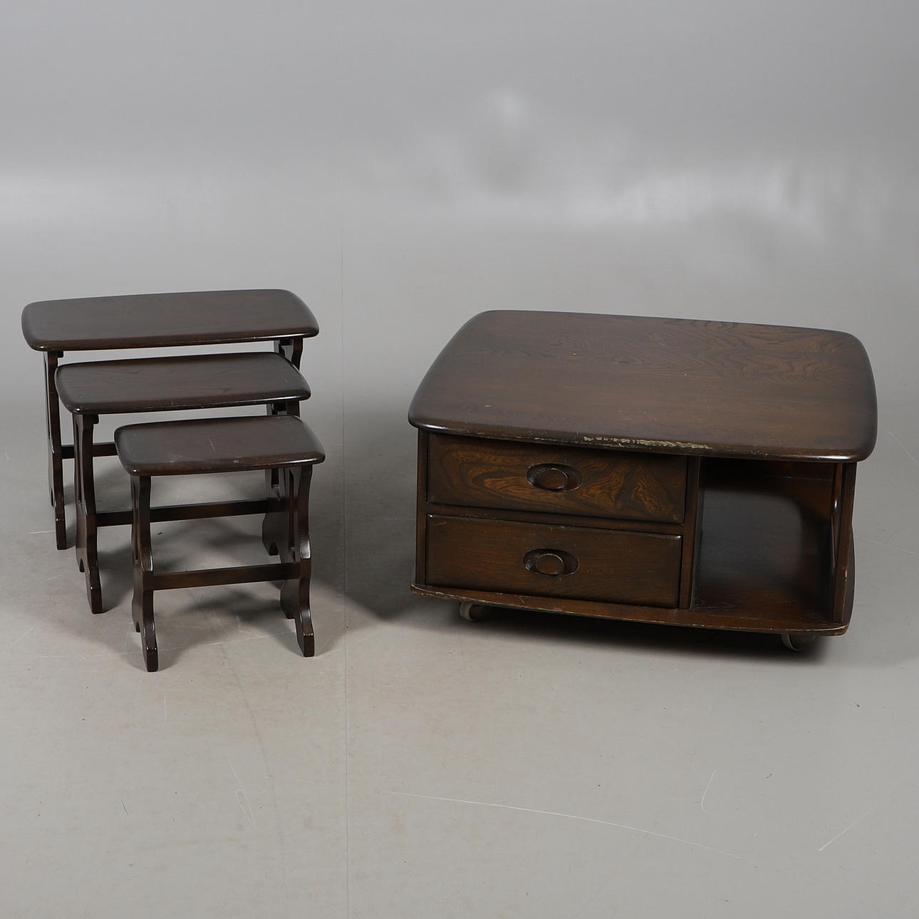 AN ERCOL DARK OAK PEBBLE COFFEE TABLE AND NESTING TABLES.
