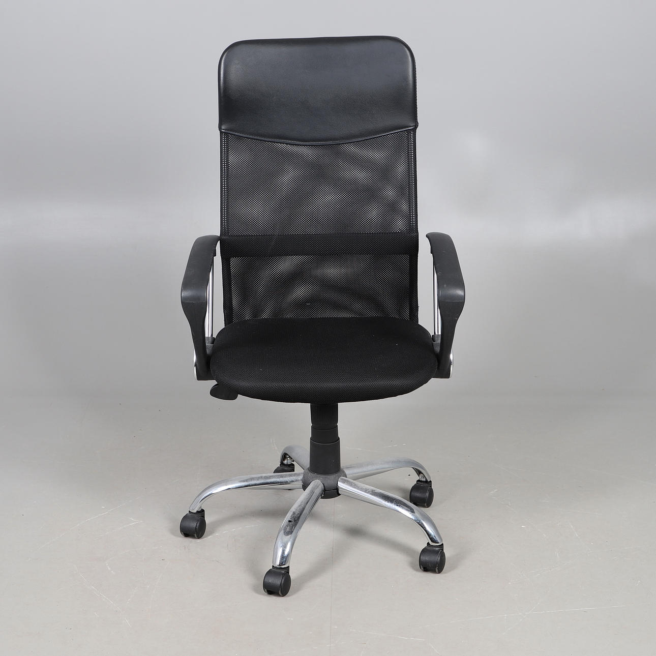 A MODERN BLACK MESH OFFICE CHAIR.