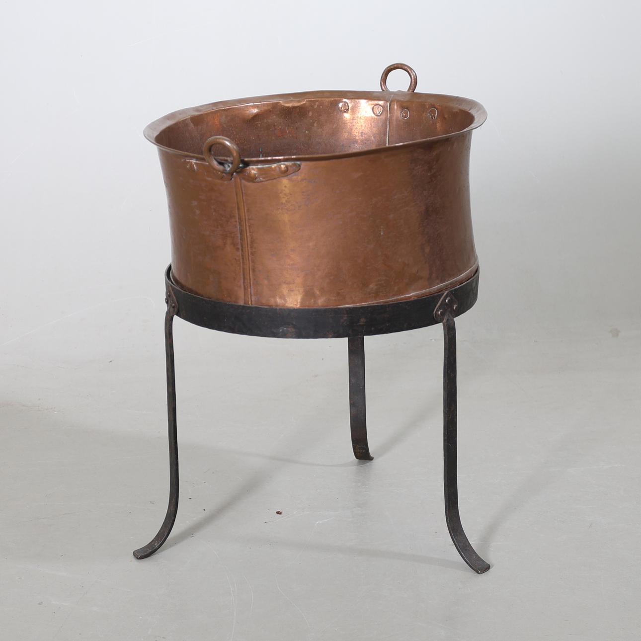 A copper cauldron, on a footrest, 20th century.