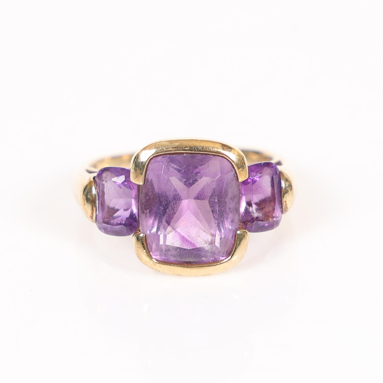 A 9 CARAT GOLD THREE STONE AMETHYST SET RING.