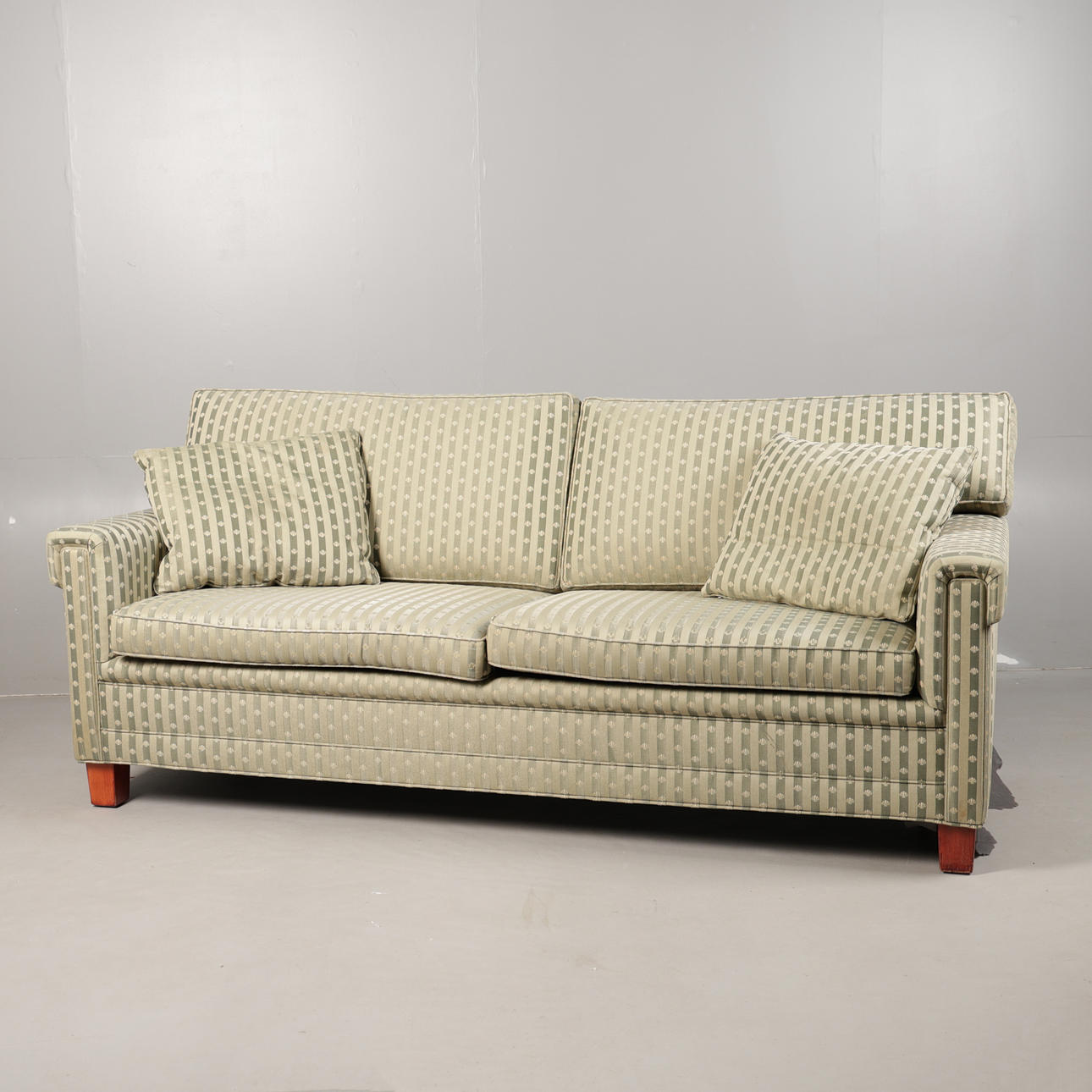 A 20TH CENTURY UPHOLSTERED THREE-SEATER SETTEE/SOFA.