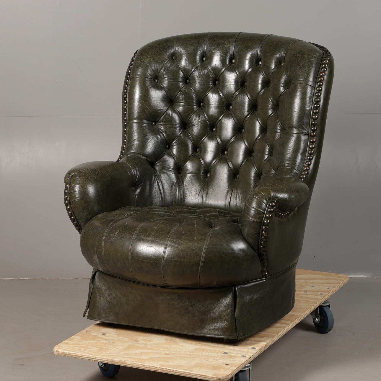 A GREEN LEATHER BUTTON DOWN ARMCHAIR.