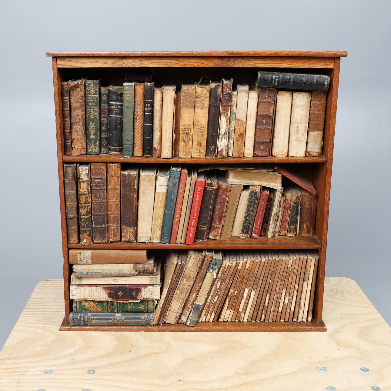 SMALL GEORGE V OAK TABLETOP BOOKCASE AND CONTENTS.