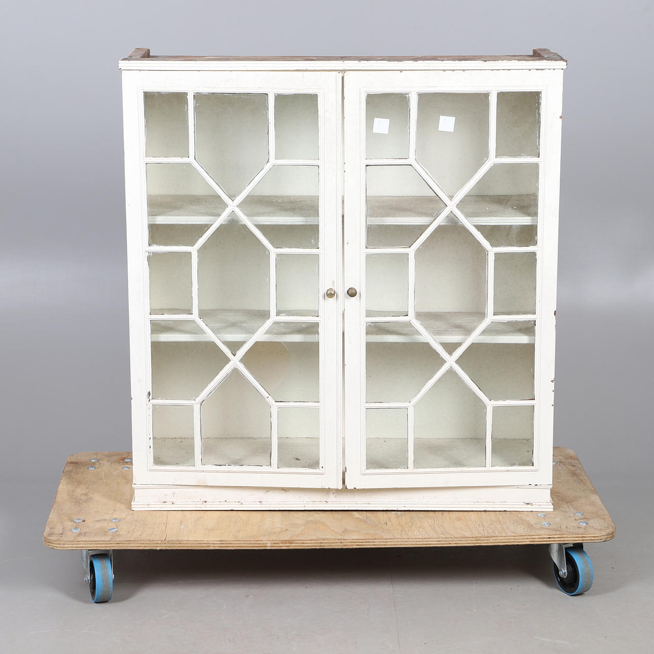 A RUSTIC GLASS FRONTED KITCHEN CABINET.
