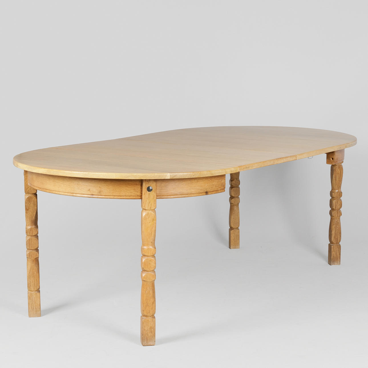 Circular dining table made of solid oak with pull-out and two additional plates, Kjærnulf-style, Danish furniture manufacturer, Denmark, circa 1960/1970s (1+2).