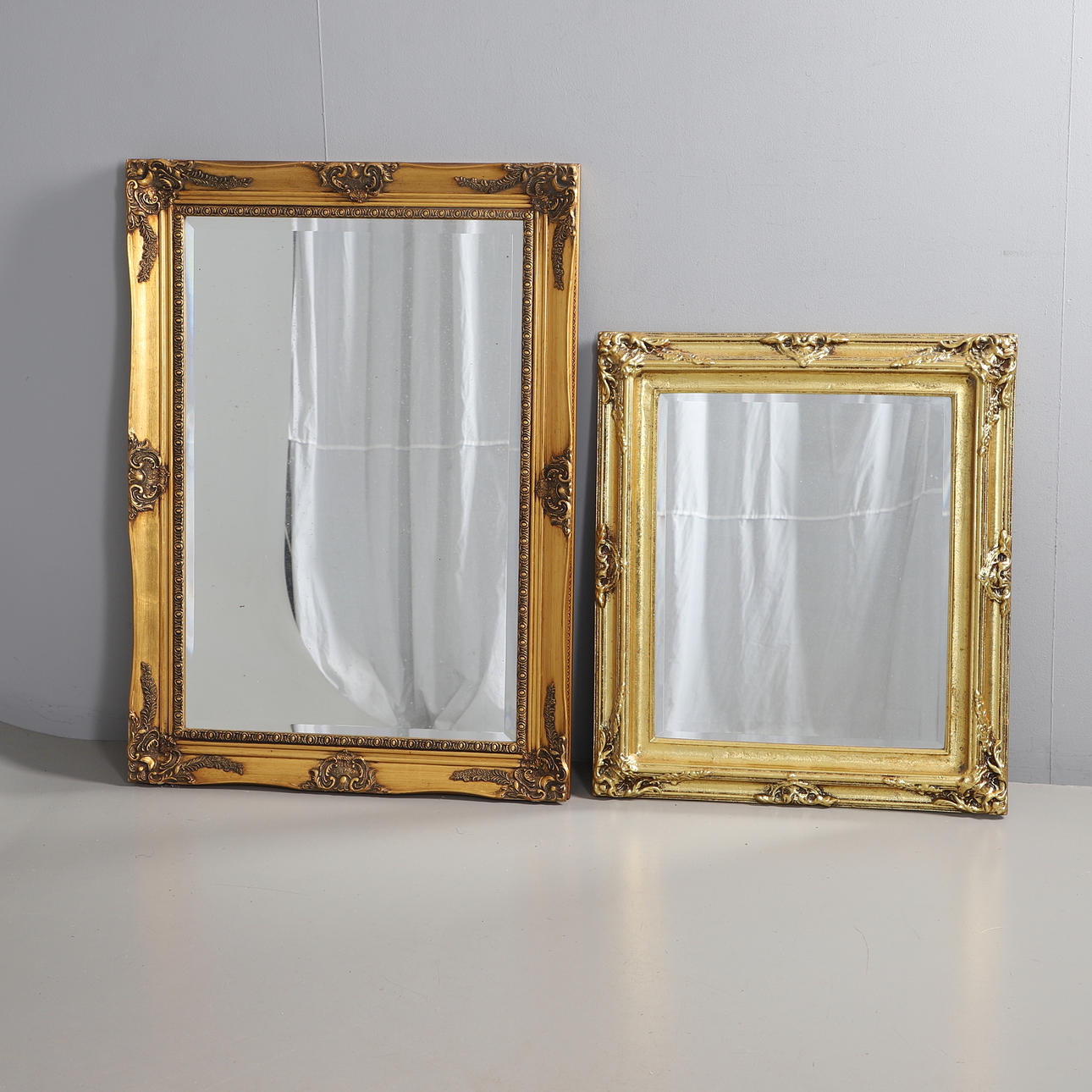 TWO MODERN GILT FRAMED WALL MIRRORS.