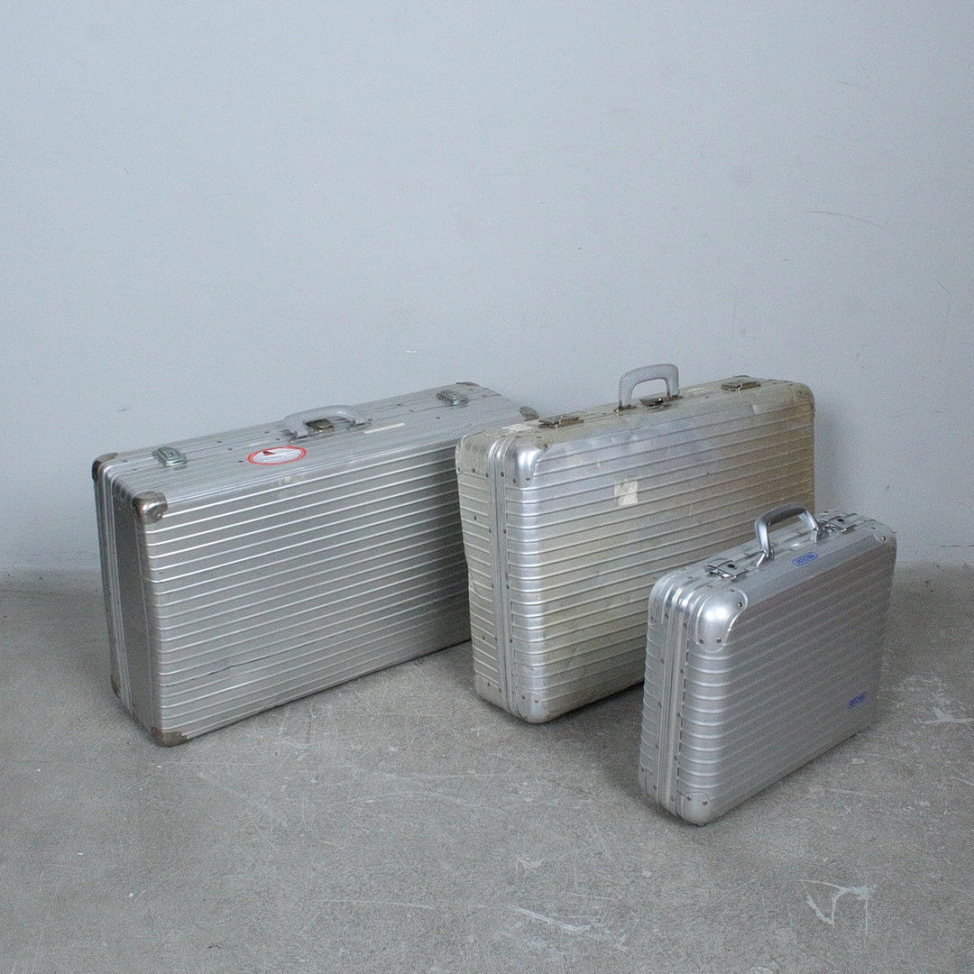 Three aluminium suitcases, including Rimowa.
