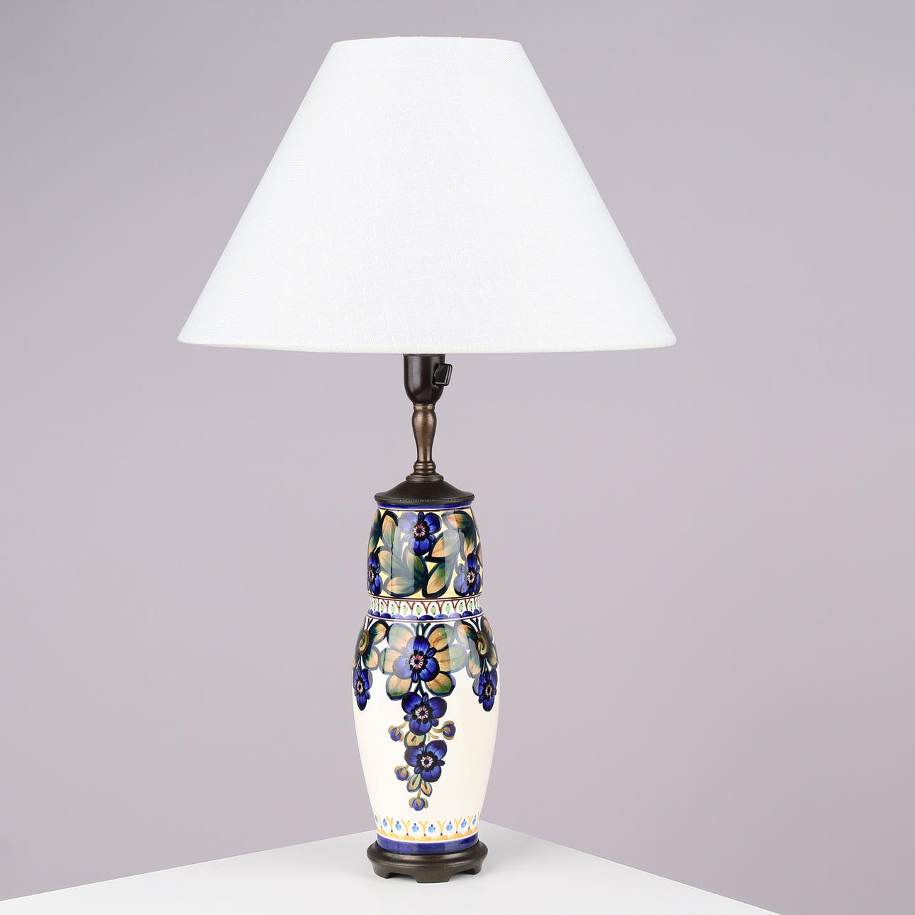 ALUMINA: Bordslampa av fajans dekorerad med handmålade blomstermotiv, fot och topp av brunerad mässing, modellnr. 1086/821, Danmark, 1900-talets första hälft.