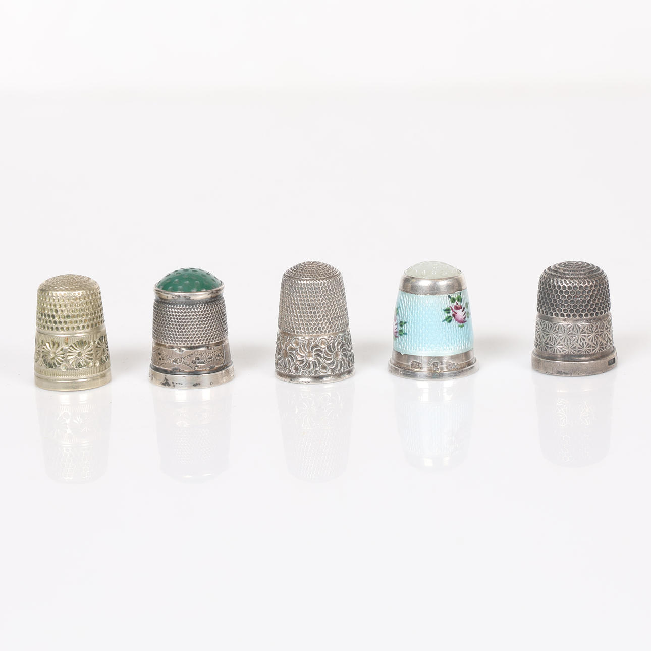 FOUR SILVER THIMBLES AND A PLATED THIMBLE (5).