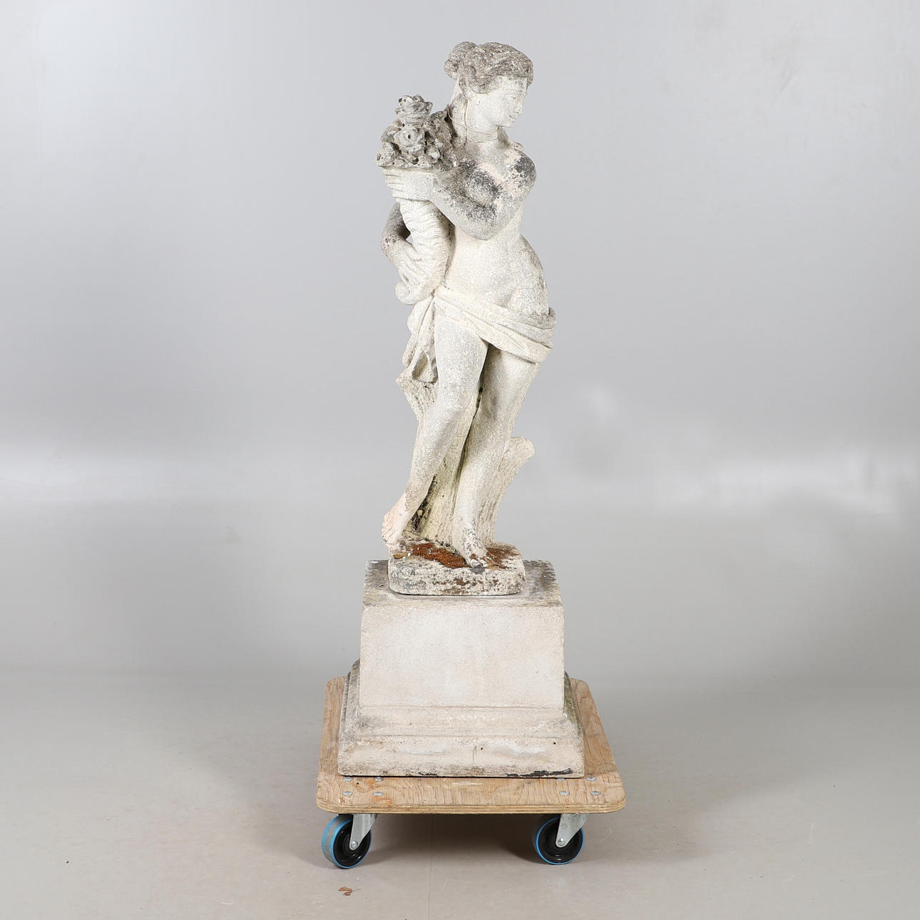 A CARVED STONE CLASSICAL MAIDEN ON COMPOSITE STAND.