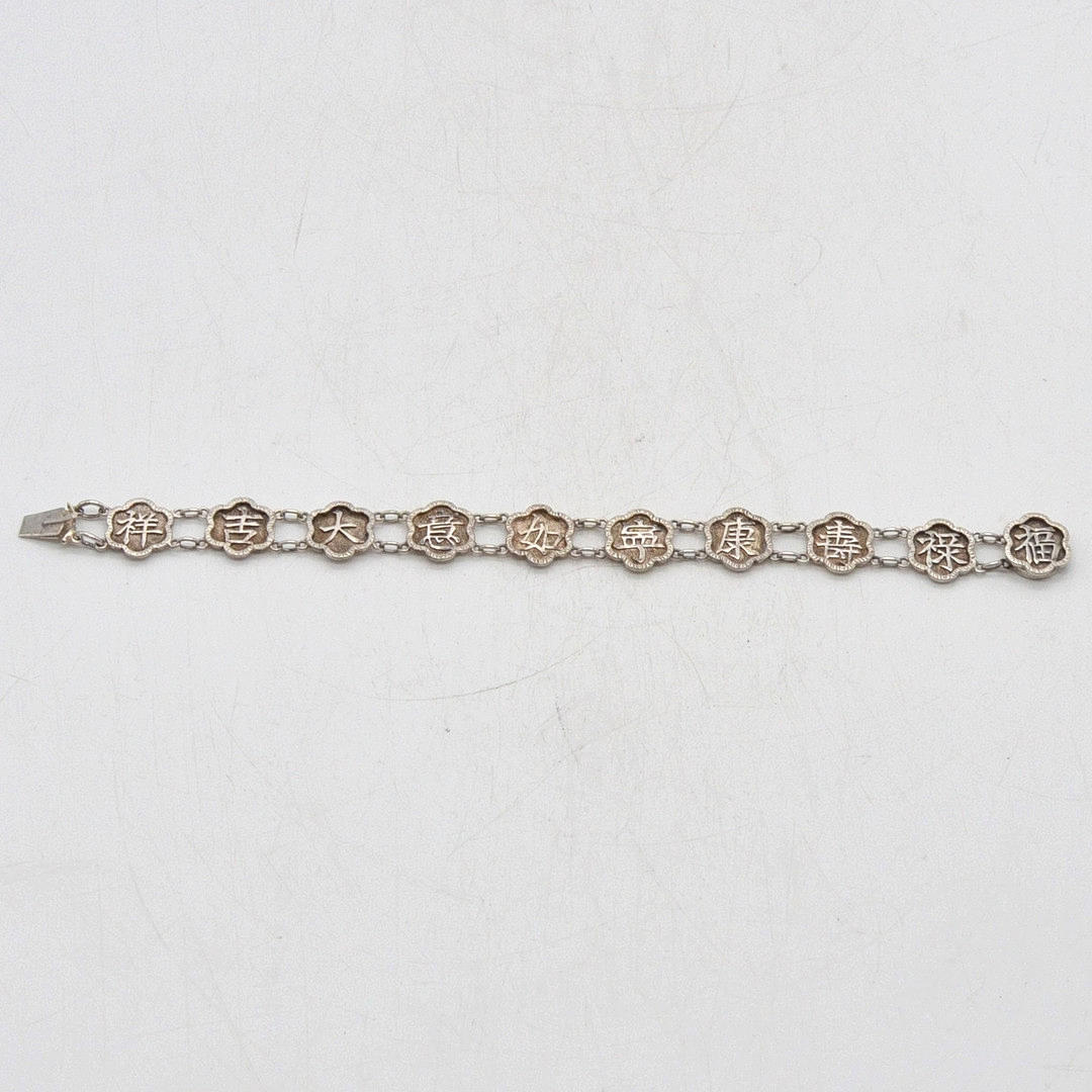 LÄNKARMBAND MED KINESISKA LYCKOORD, INFATTNING I STERLINGSILVER, BLOMFORM, AV "C.M.", MITTEN AV 1900-TALET