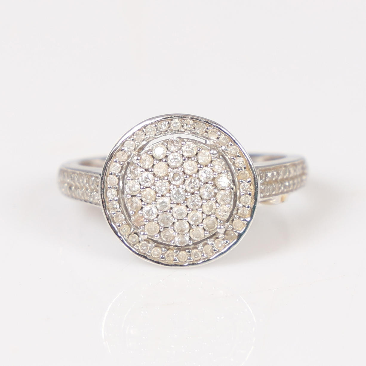 A 9 CARAT WHITE GOLD DIAMOND CLUSTER RING.