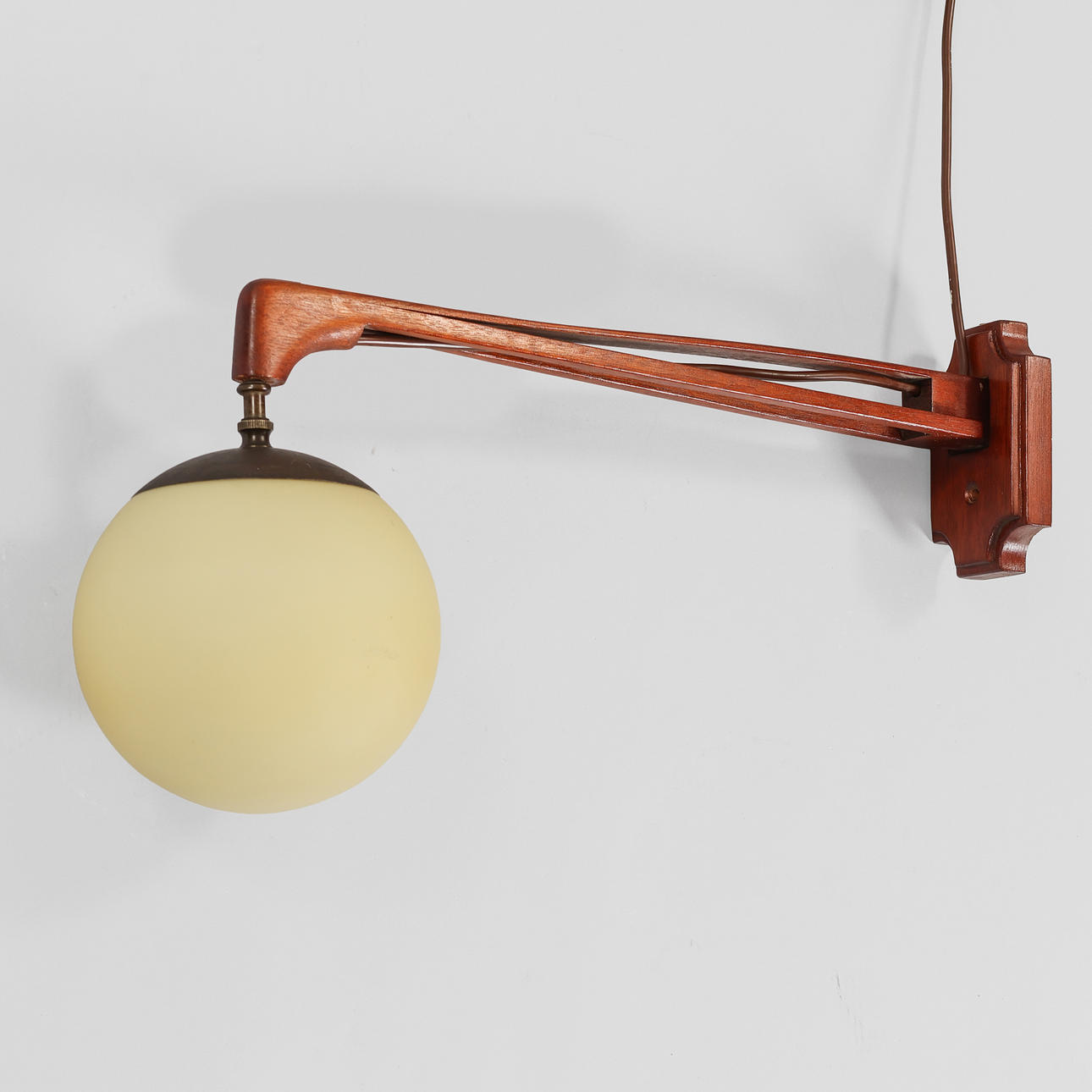 Attributed to LYFA. Adjustable wall lamp in solid teak with champagne-coloured glass shade, first half of the 20th century.