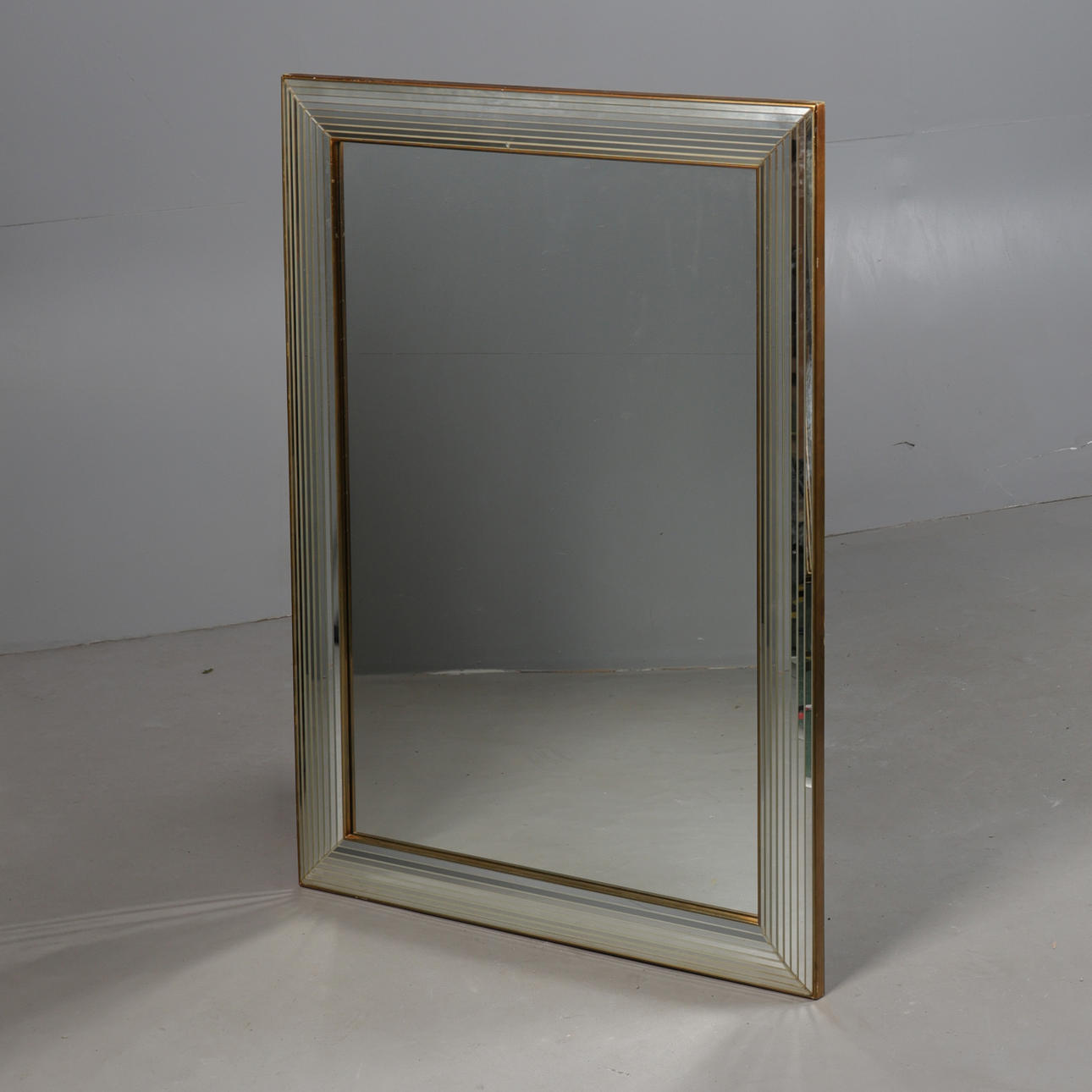 A CONTINENTAL GILT FRAMED AND BEVELLED WALL MIRROR.