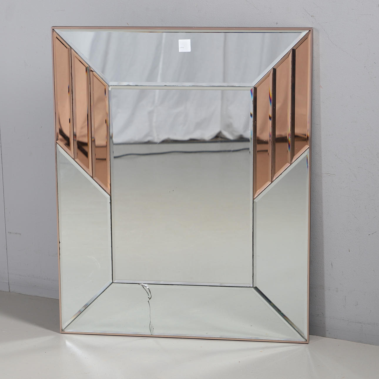 A CLEAR AND PEACH GLASS WALL MIRROR.