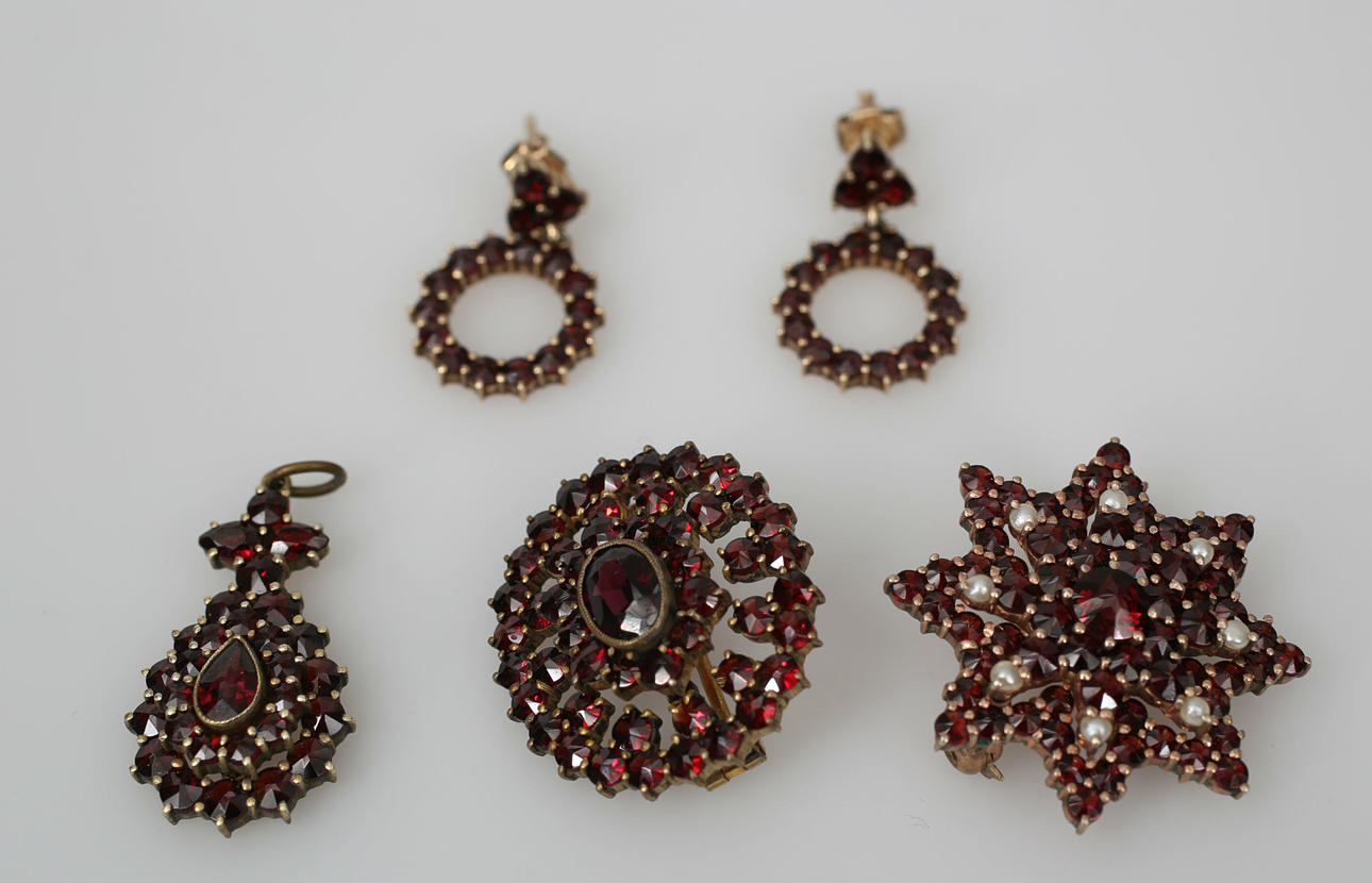 BROSCHER, HÄNGE OCH ÖRHÄNGEN, delvis förgyllt silver, granater och pärlor, 5 delar, 1900-tal.