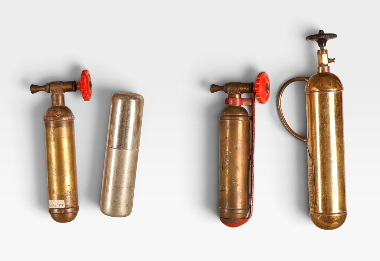 Four small brass and iron hand-held fire extinguishers.
