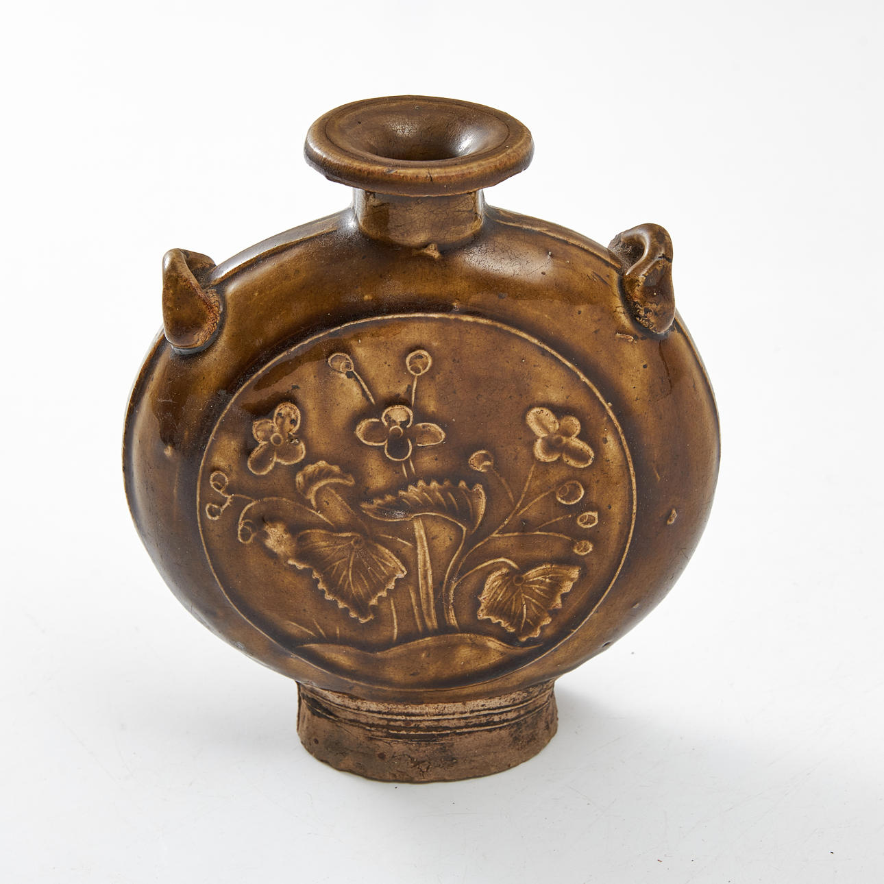 PILGRIM FLASK, earthenware, China, likely Ming (1368-1644), circular, with handles, decorated with prunus trees and flowers and leaves in relief, brown glaze.