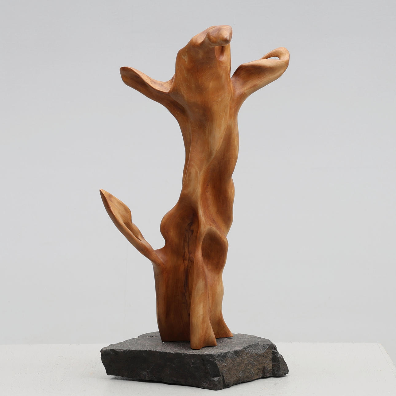 Tony Ljungberg. Abstrakt skulptur, i trä, på stensockel.