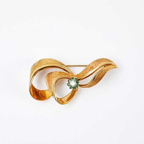 BROSCH, 18 k guld, 1 briljantslipad diamant, ca 0,10 ct, krans med fasettslipade smaragder, i form av rosett. på auktion hos Stockholms Auktionsverk Sickla
