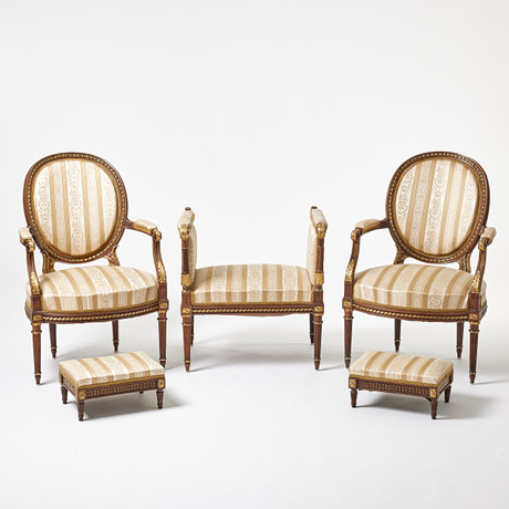 KARMSTOLAR med FOTPALLAR samt en BANKETT, Louis XVI-stil, fem delar, metall dekor. på auktion hos Stockholms Auktionsverk Magasin 5