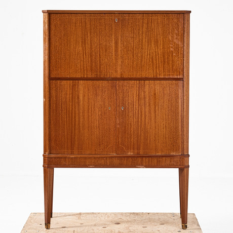 BARSKÅP, 1950-tal, med spegelinredning, fanerad i mahogny, fothylsor i mässing, med belysning, intarsia dekor, på auktion hos Stockholms Auktionsverk Magasin 5