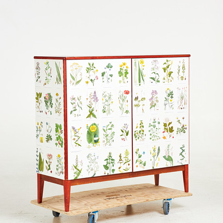SKÅP, 1900-talets mitt, fanerad med mahogny, senare tapetserad med Nordens Flora, invändigt med hyllplan samt på auktion hos Stockholms Auktionsverk Sickla