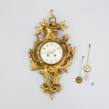 VÄGGPENDYL, sk KARTELLUR, Louis-XV stil, förgylld metall, omkring sekelskifte 1900. på auktion hos Auktionshuset Kolonn