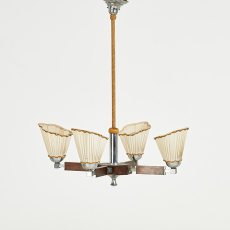 TAKLAMPA, Art Deco, delvis replindad stomme i vitmetall, samt betsad teak, fyra ljusarmar, skärmar i textil, 1 på auktion hos Stockholms Auktionsverk Sickla