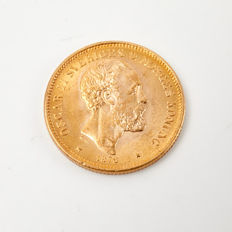MYNT, 21,6 k guld, Oscar II, 20 kronor, 1876, med etui och certifikat från Mynthuset Moneta. på auktion hos Stockholms Auktionsverk Sickla