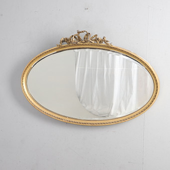 AN EDWARDIAN GILT FRAMED OVAL WALL MIRROR.