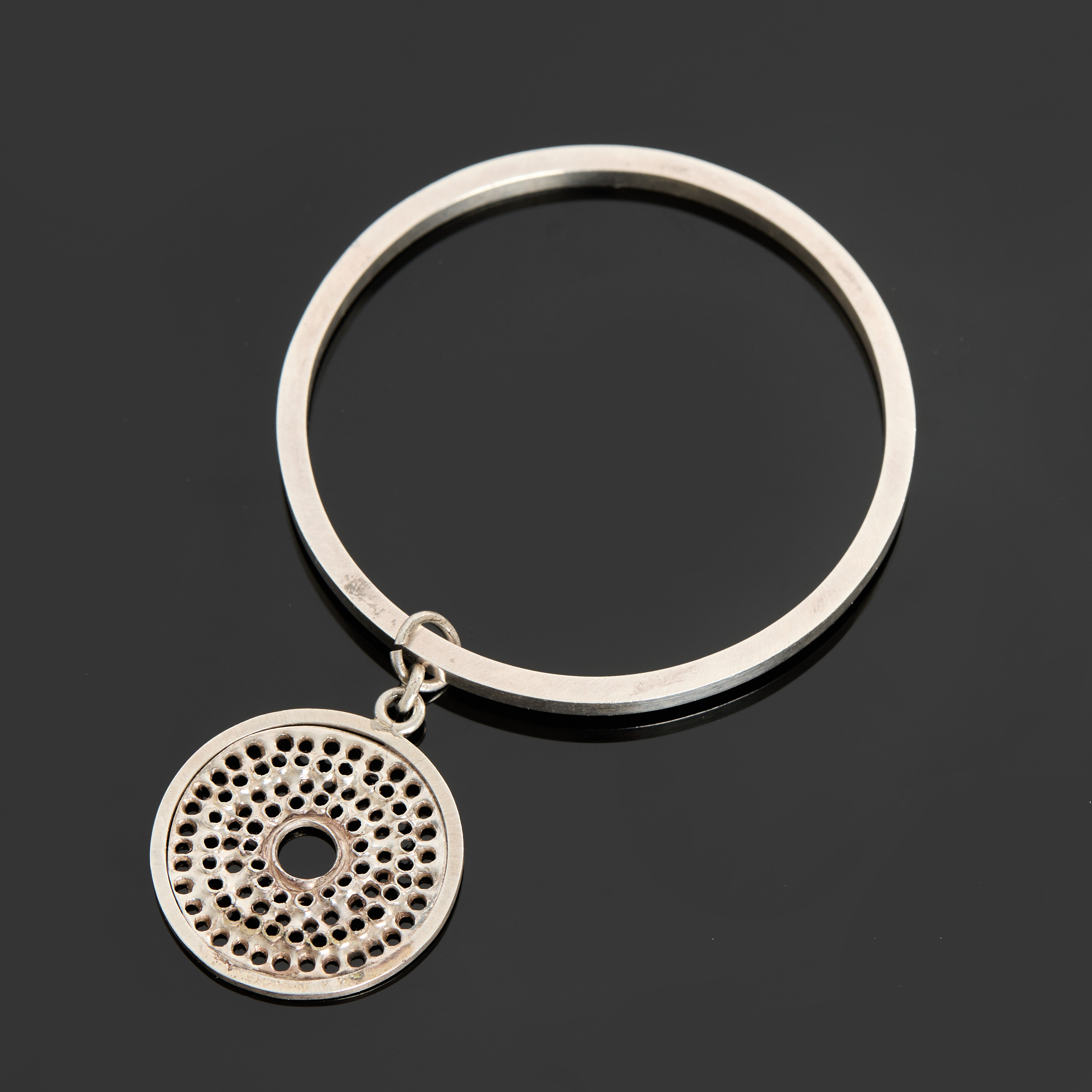 LARS ARBY (SVERIGE, 1933-2002). ARMRING MED HÄNGE, sterlingsilver, signerad, genombruten dekor, 1967, Göteborg.