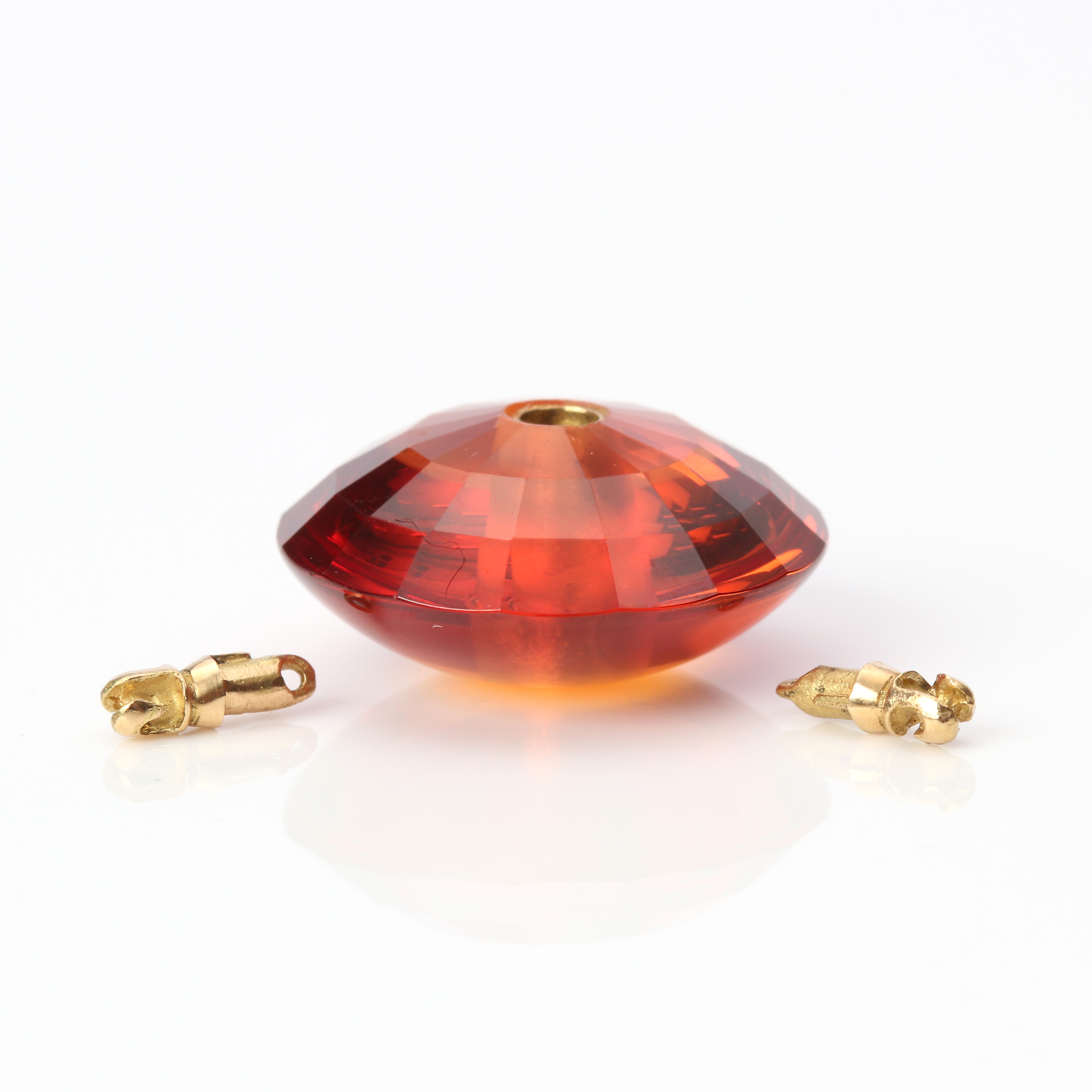 COLLIERLÅS. Syntetisk orange safir, delvis fasetterad, stift och montering i 18k guld, totalvikt 6,8 gram.