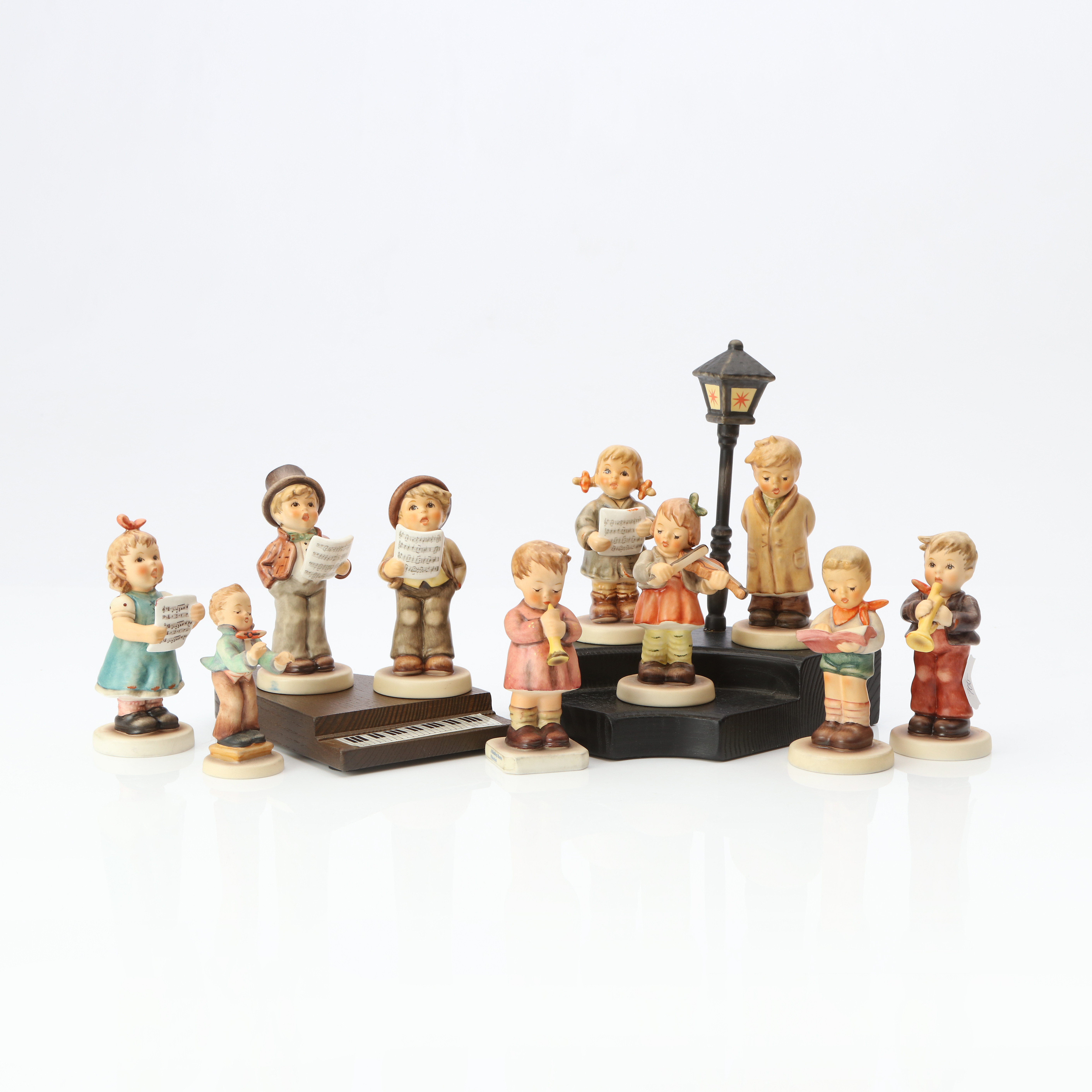 HUMMEL, FIGURINER, 10 ST. Keramik. Musikanter, med ett ställ samt sockel i form av piano. Tyskland, 1900-tal.