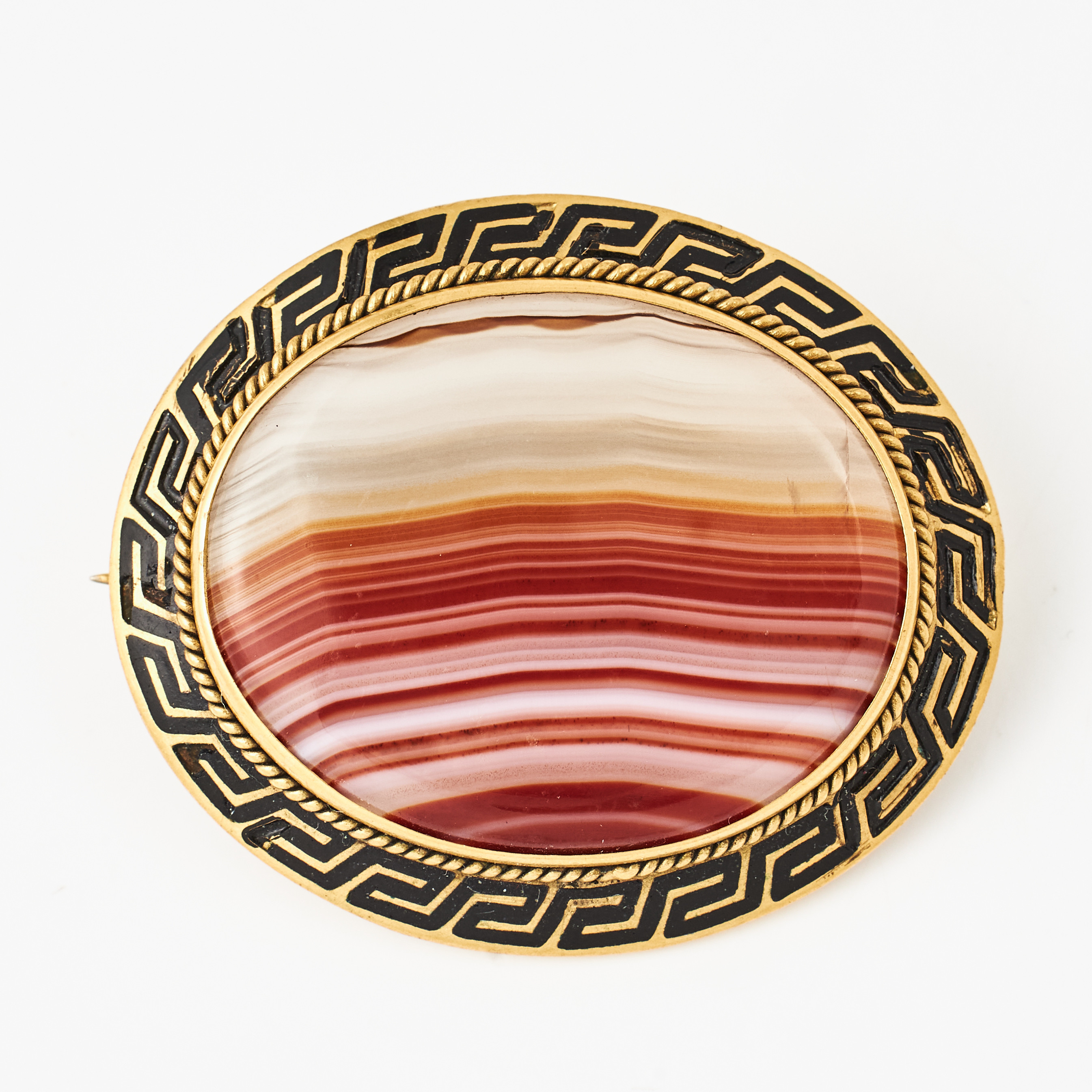BROSCH, mässing, oval agat, montering med svart emalj föreställande meanderslinga, omkring 1900.