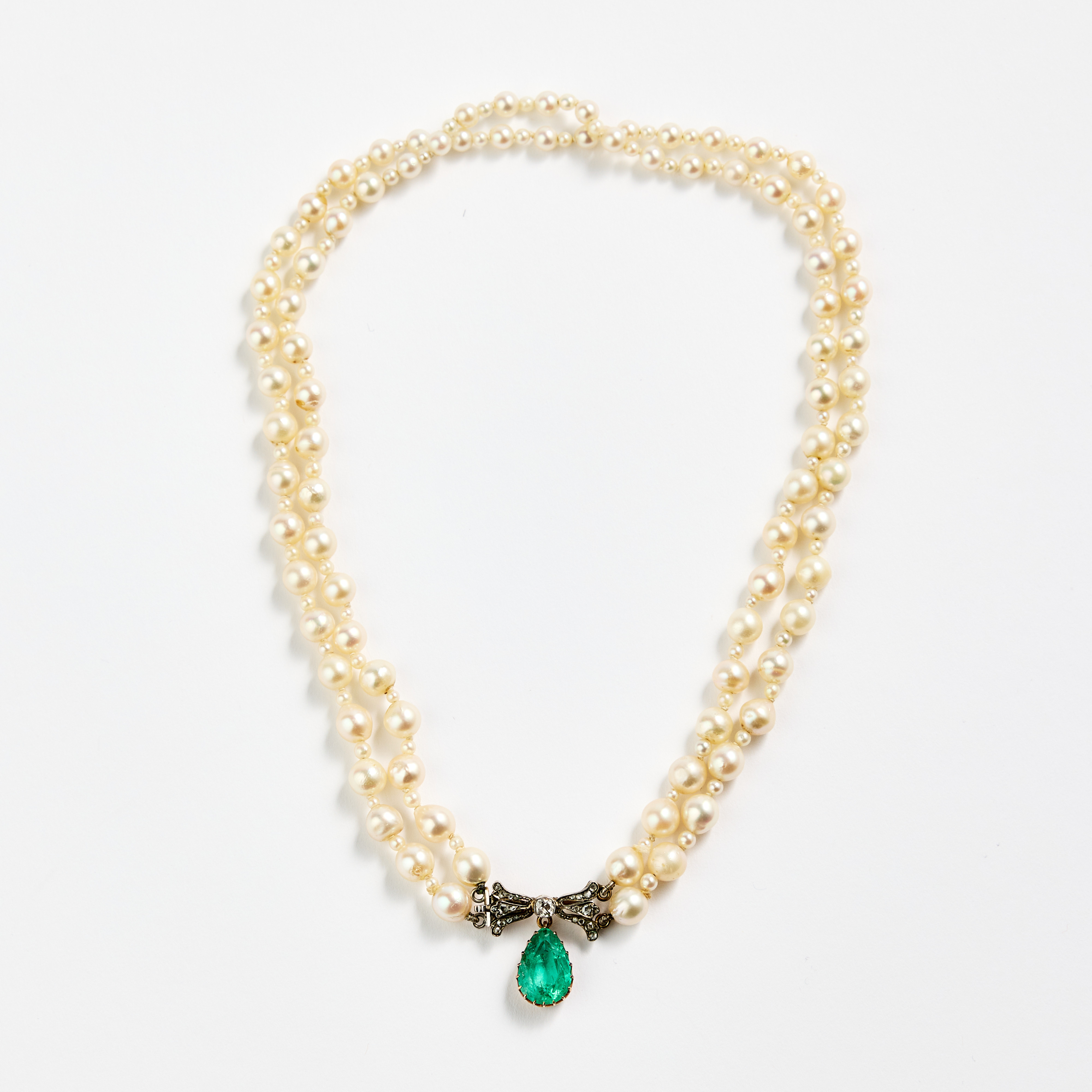 PÄRLCOLLIER, två rader odlade saltvattenpärlor. Lås i silver och guld med en smaragd och diamanter, omkring sekelskiftet 1900.
