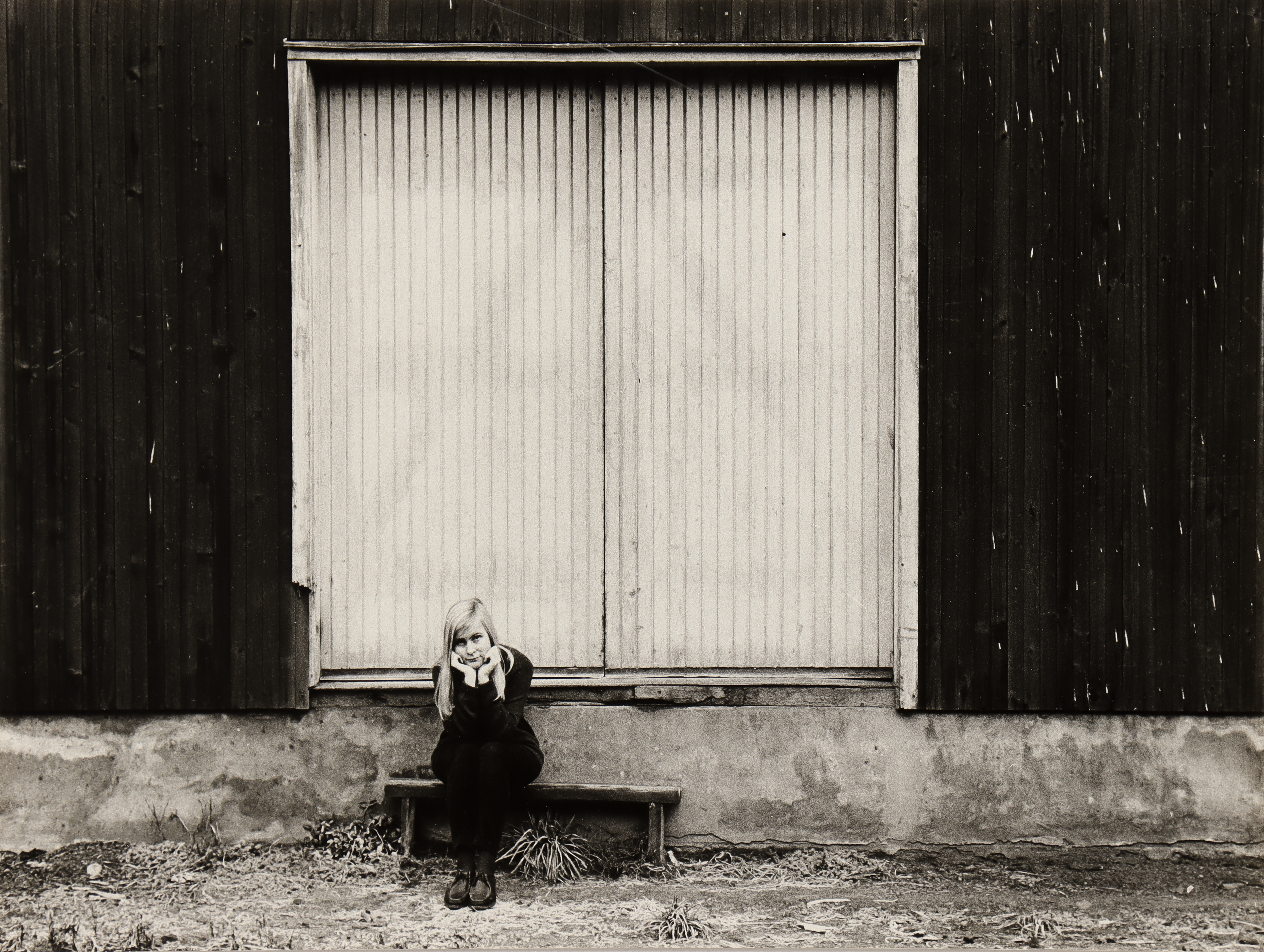 NILS-ERIK WIKEBÄCK. Kvinna sittandes utanför port.