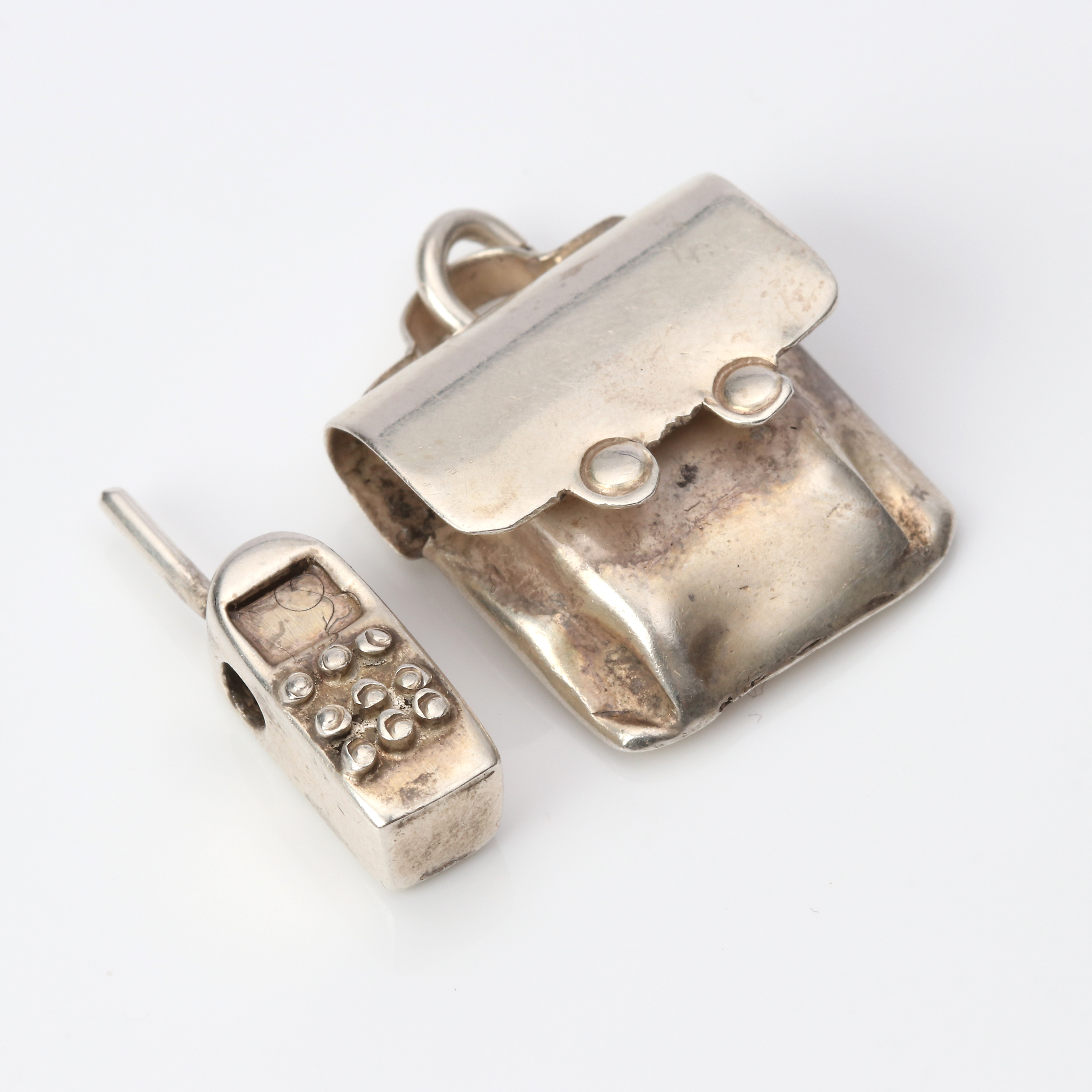 KARIN FERNER, HÄNGEN, TVÅ ST. Sterlingsilver, i form av en telefon och en väska.