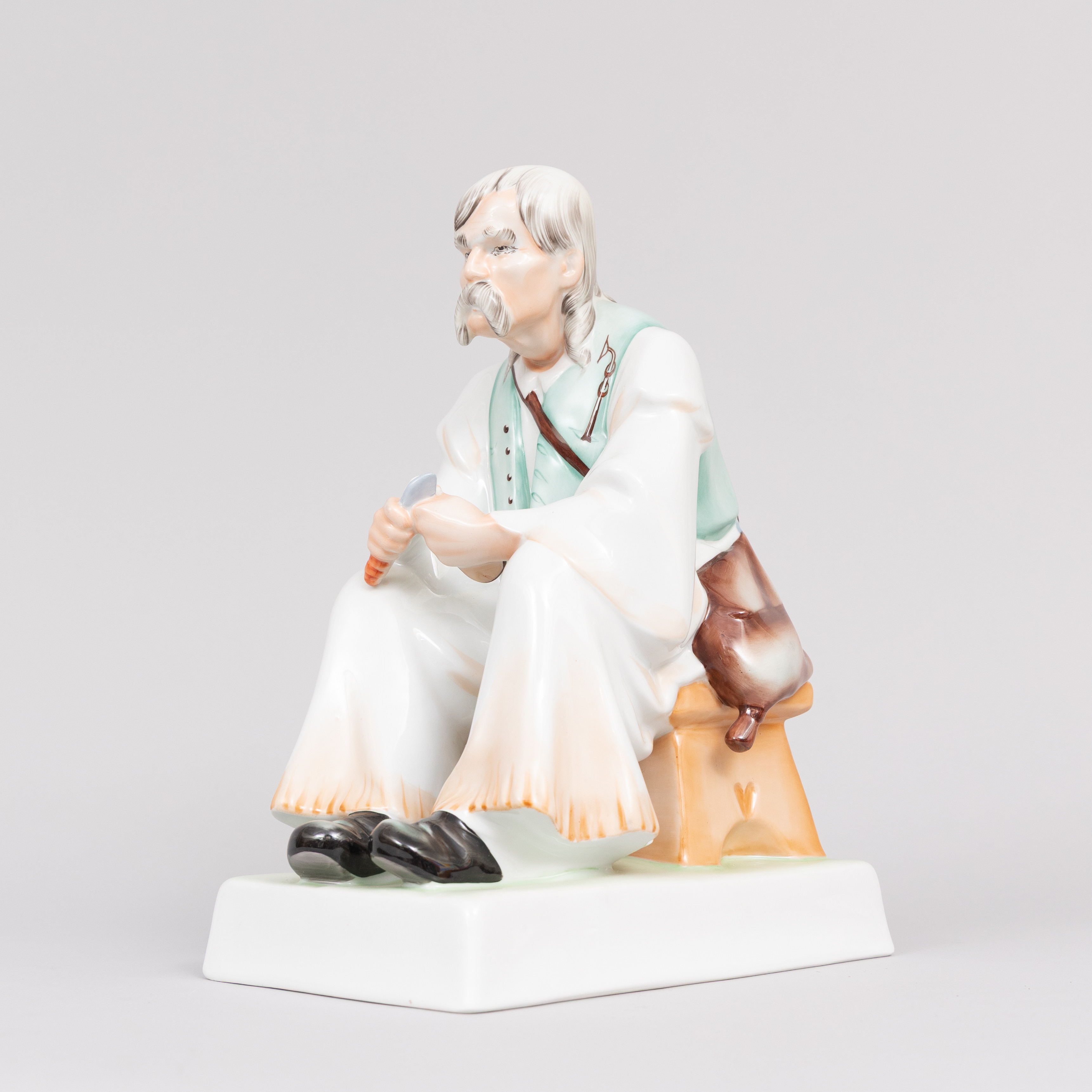 FIGURIN. Porslin. Sittande täljande man. Zsolnay, Pécs. Ungern.