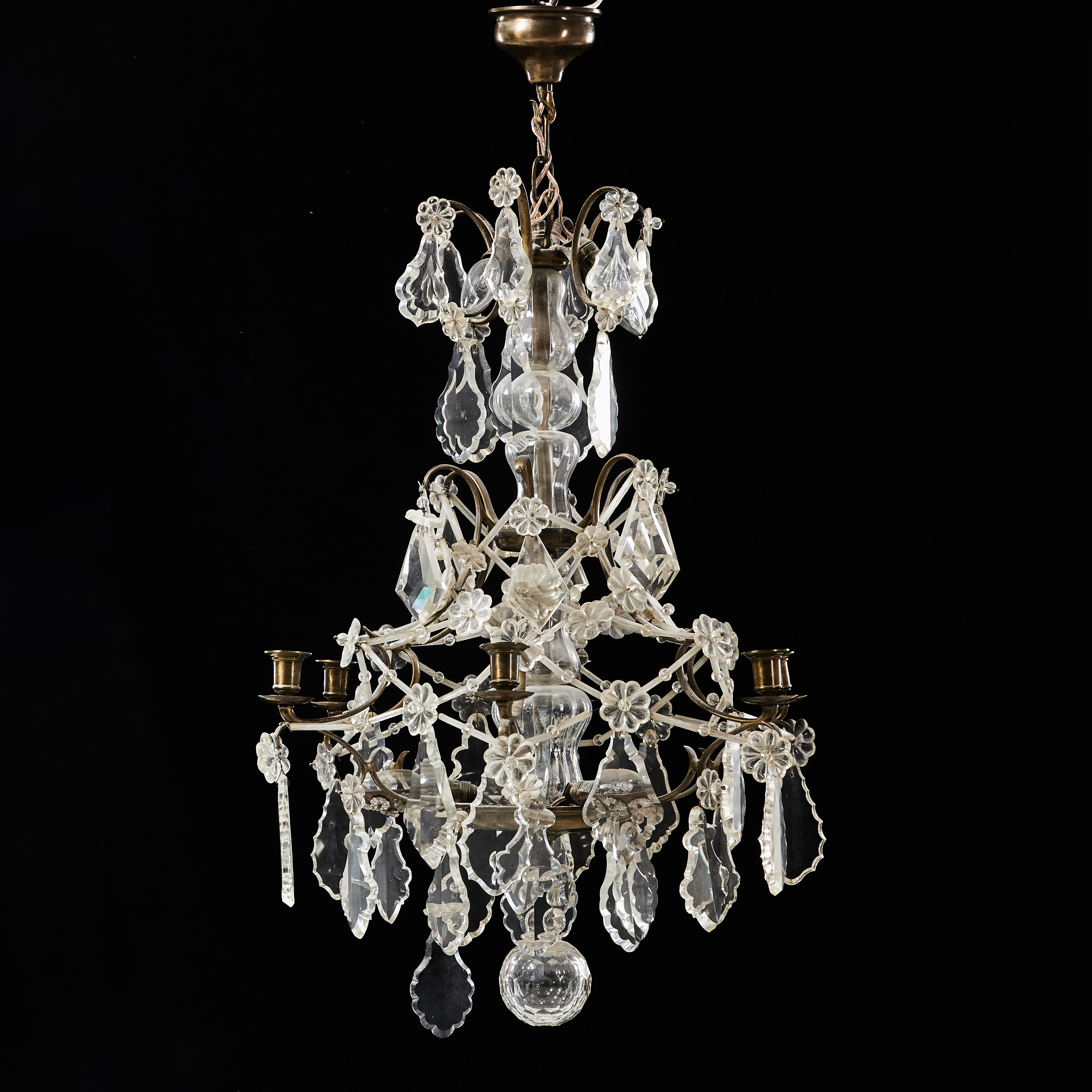 LJUSKRONA, rokokostil, 1900-talets första hälft. Stomme av mässing, behängd med prismor och stavar. Sex ljuspunkter.