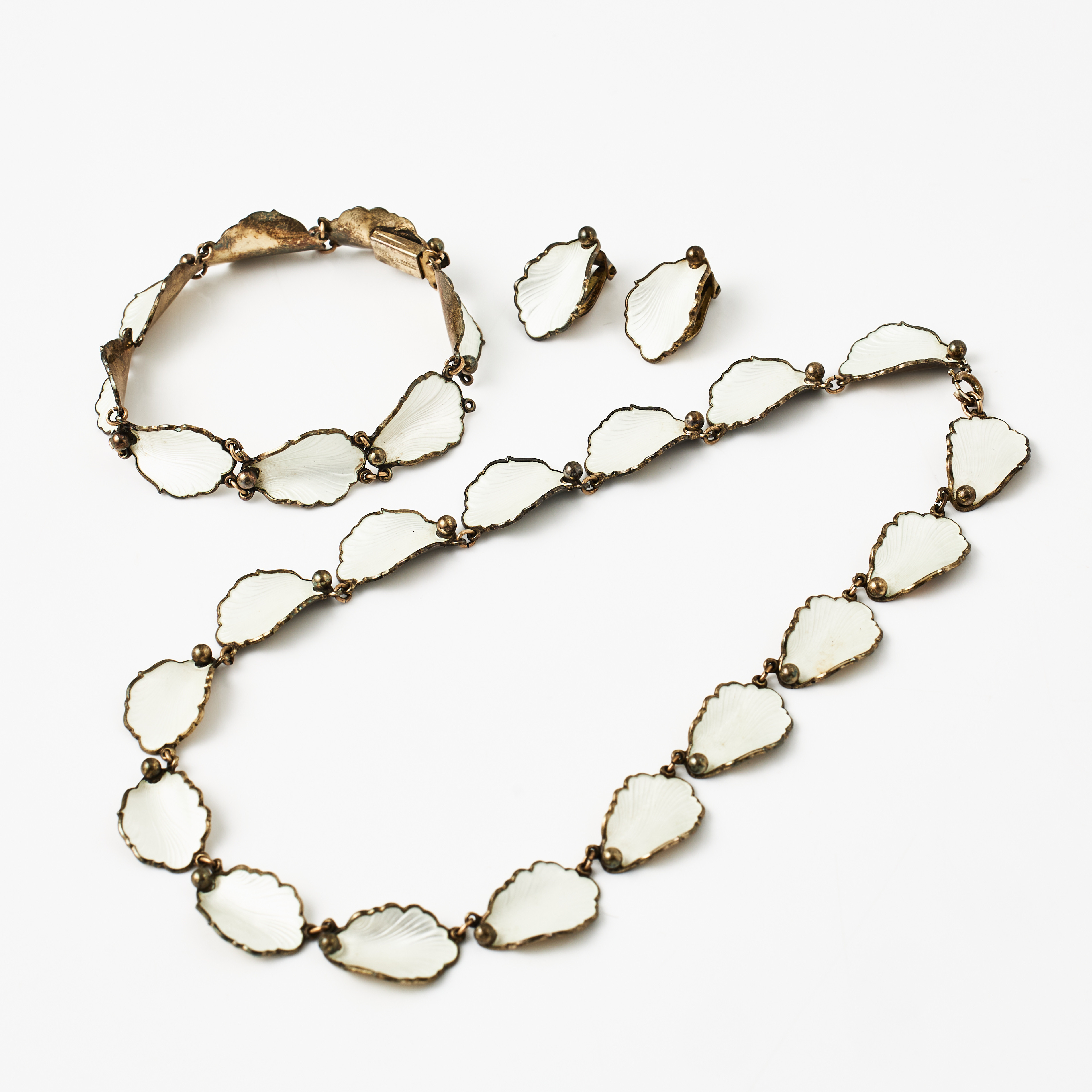 HANS MYHRE, armband, collier, clips, 1 par, förgyllt sterlingsilver, lövformationer med dekor av guillocherad gräddvit emalj, Norge.